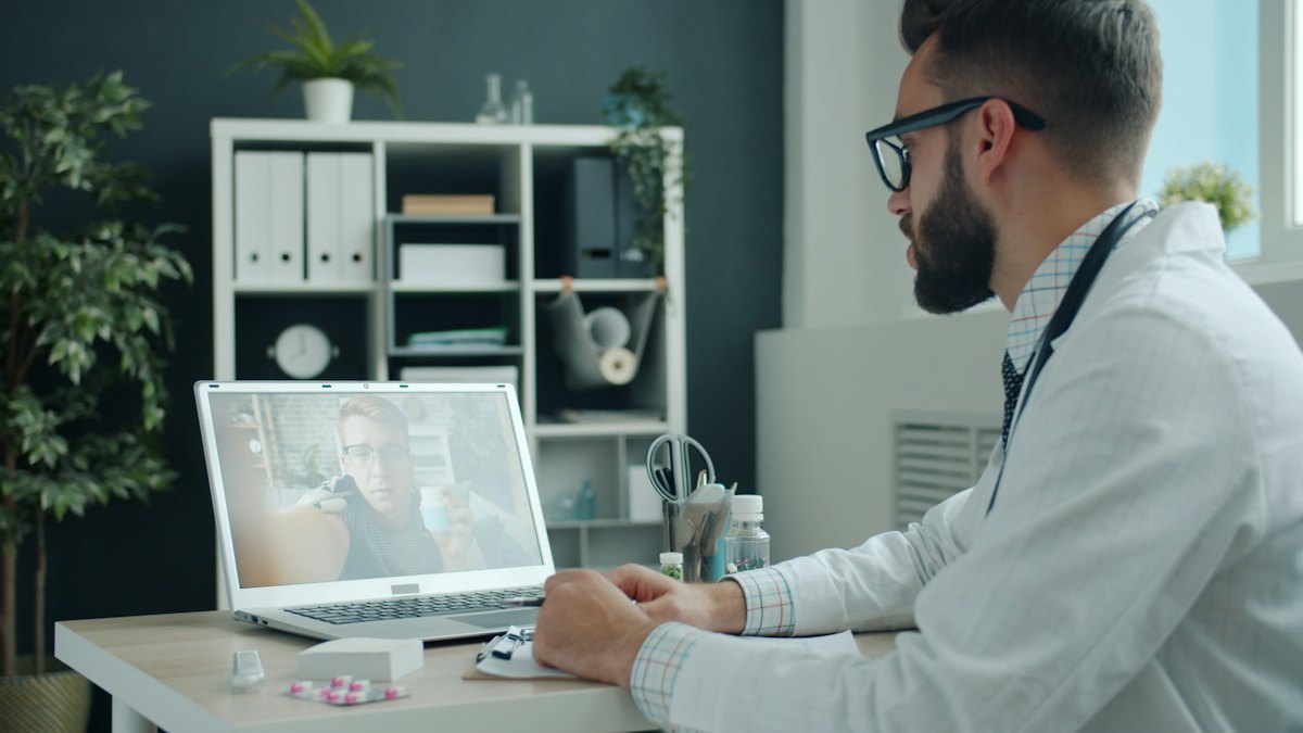 Doctor in a white coat on a video consultation with a patient on a laptop